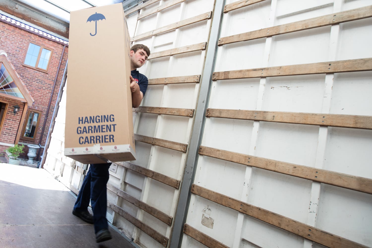 Steeles Removals employee carrying hanging garment carrier during house move