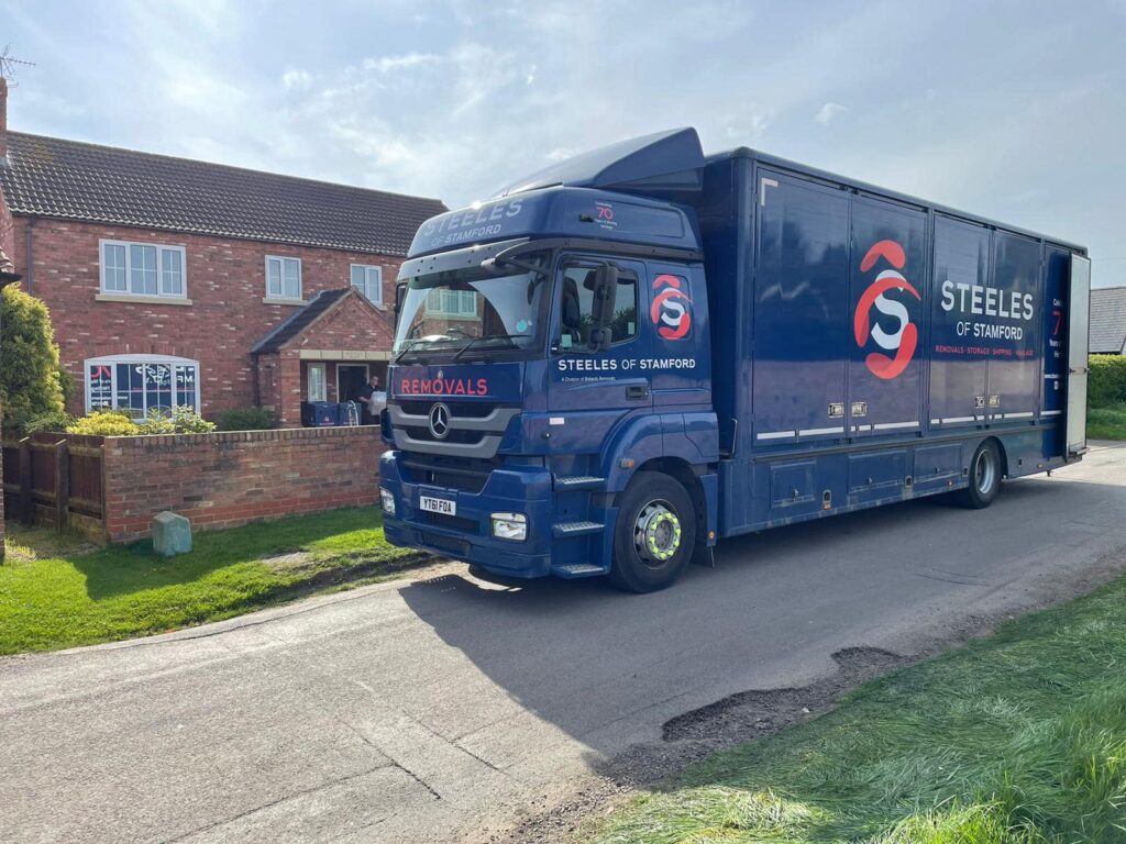 A Steeles of Stamford removals lorry parked in front of a house in sunny weather